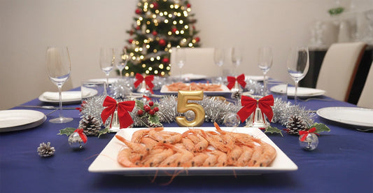 Una mesa elegante con una vela dorada de celebración de 5º aniversario, un plato de marisco y decoración de navidad elegante.